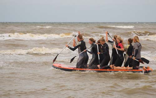 Mega SUP Zandvoort. Sup op een heel groot surfboard met je 10 persoons groep. Paddel door de branding heen en surf terug! Mega sup Zandvoort